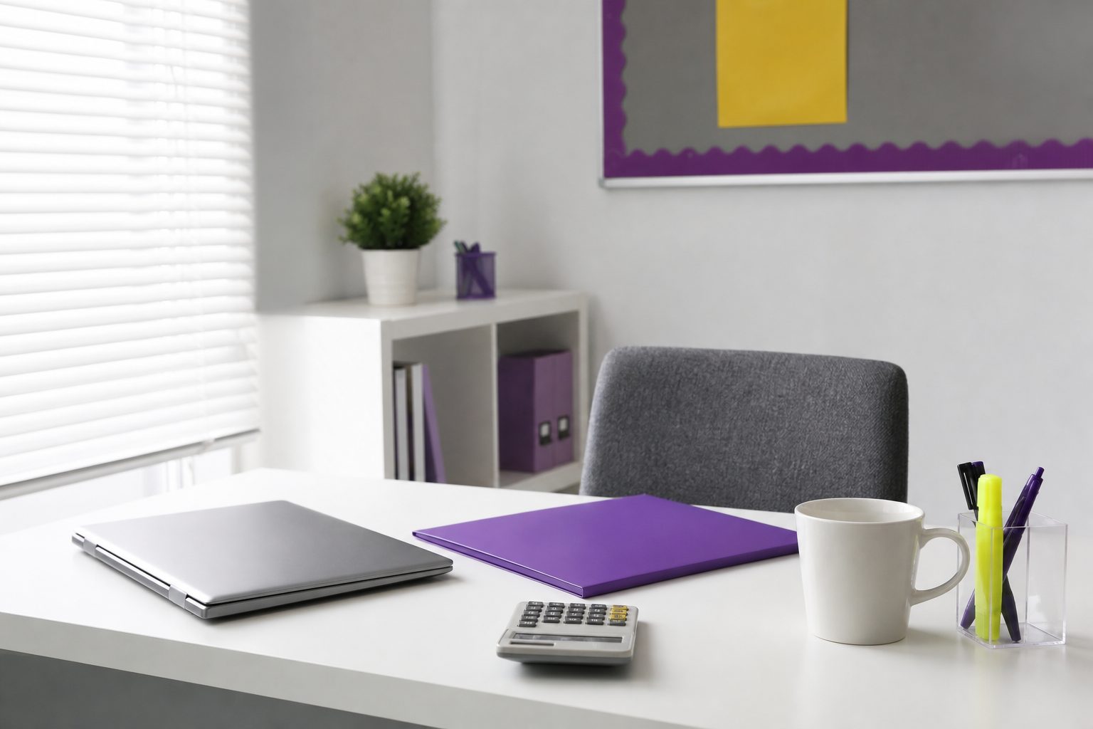A tidy tutoring center desk with a closed laptop, violet folder, calculator and mug in bright daylight